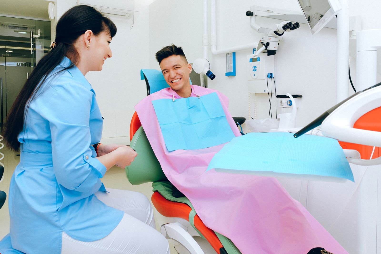 Smiling patient in a dental chair talking with a dentist
